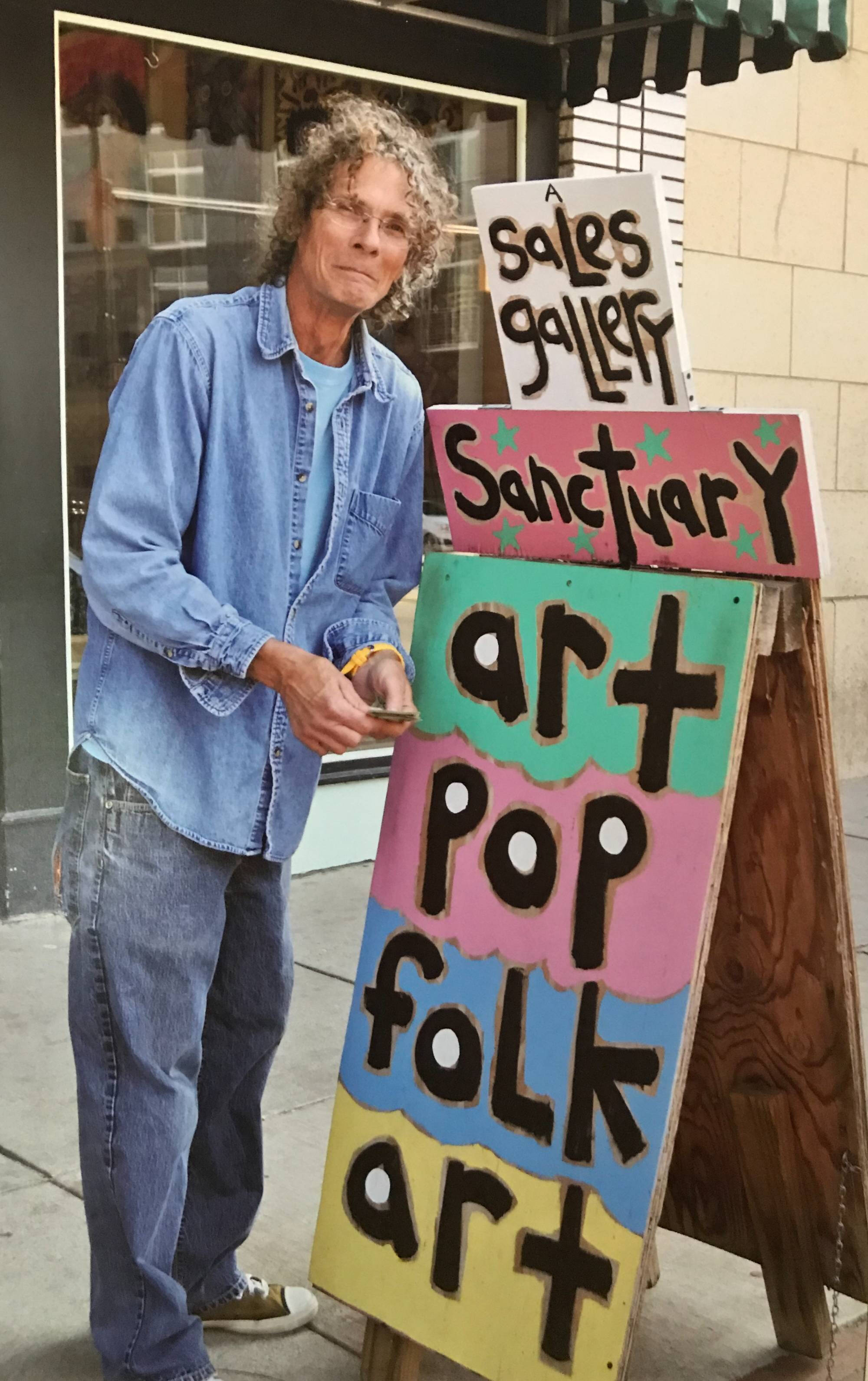 Reb Roberts with a sign for his art gallery.